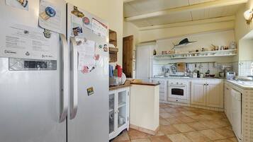 A kitchen with white cabinets, a stainless steel refrigerator, and a tiled floor.