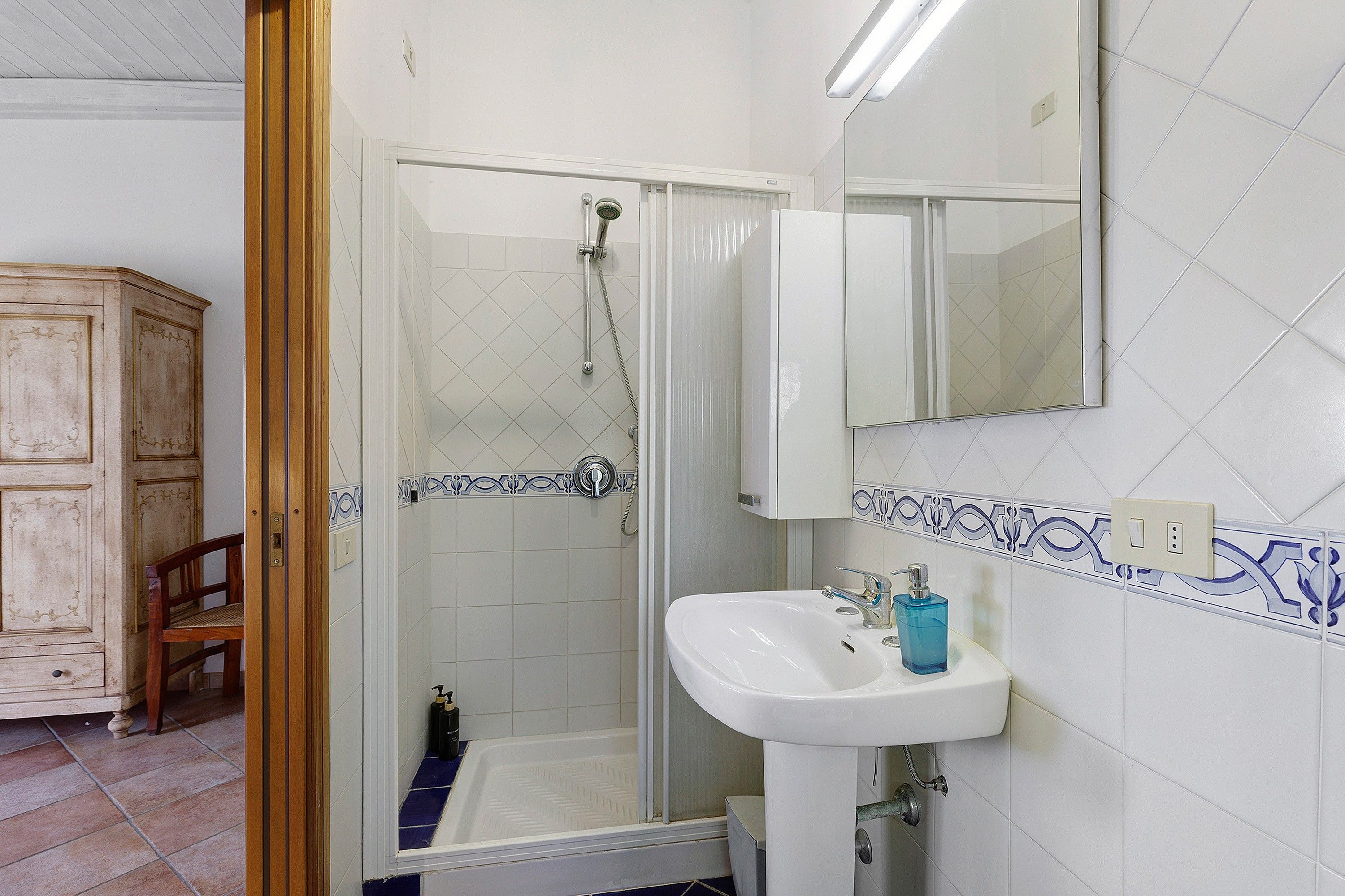 Une salle de bain avec une douche, un lavabo et un meuble de rangement.