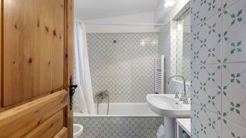 A bathroom with a wooden door, a shower with a curtain, a bathtub, and a sink.