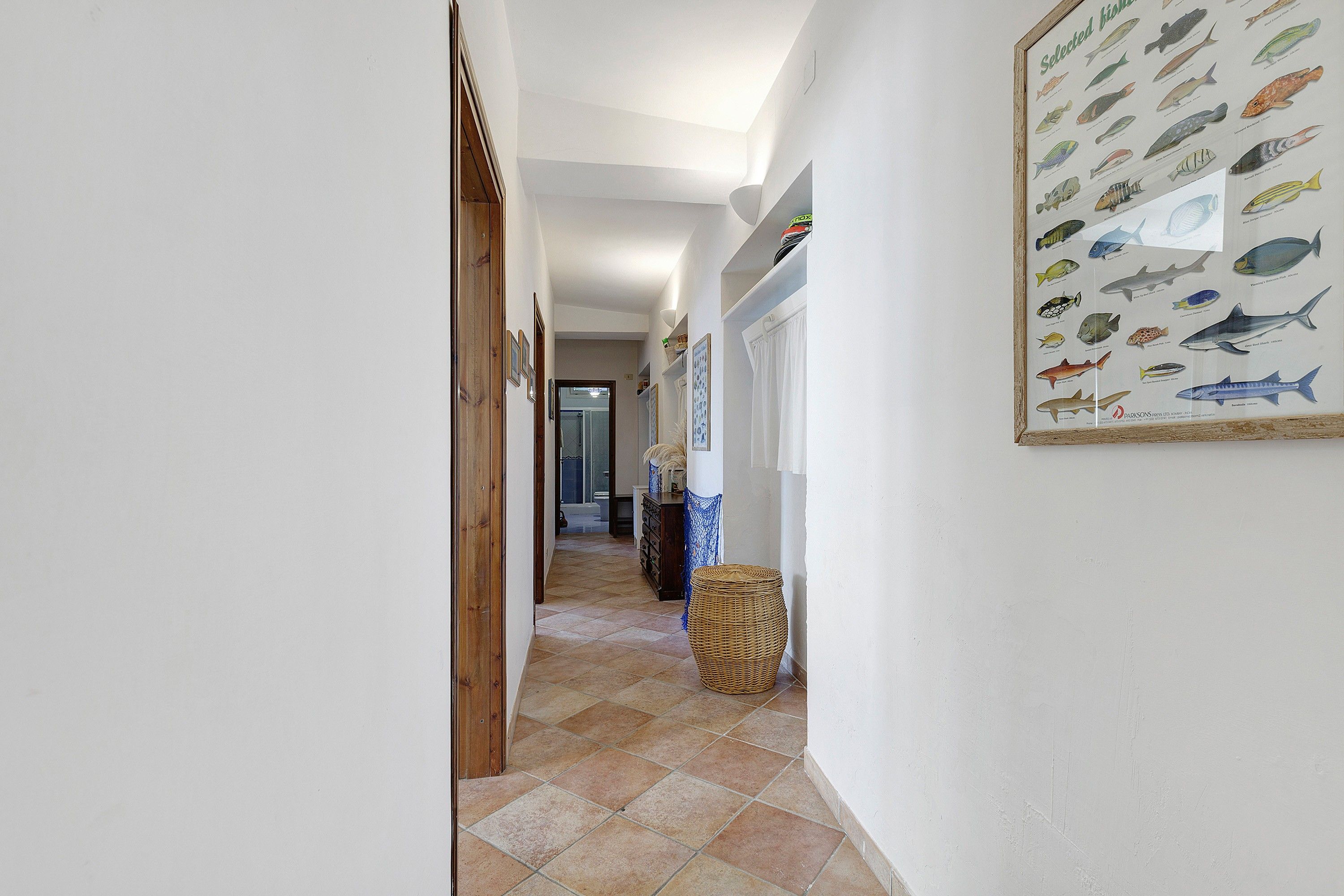 A hallway with a fish wall art, a wicker basket, and a wooden door.
