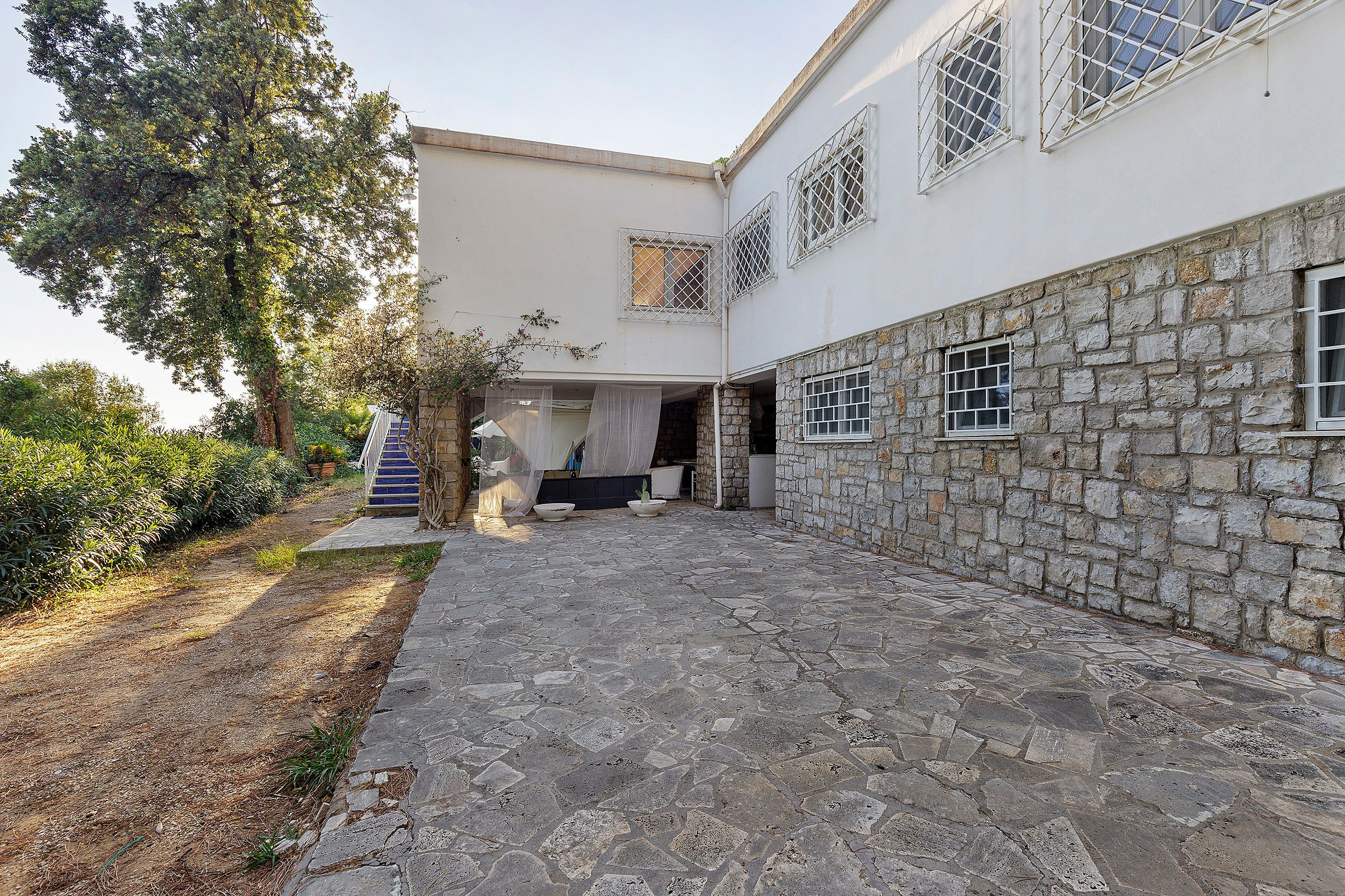 A building with a stone facade, a covered outdoor area, and a staircase leading to a door.