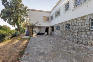 A building with a stone facade, a covered outdoor area, and a staircase leading to a door.