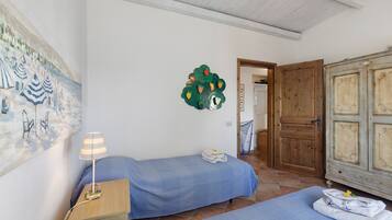 A room with two beds, a lamp, a painting, and a door.