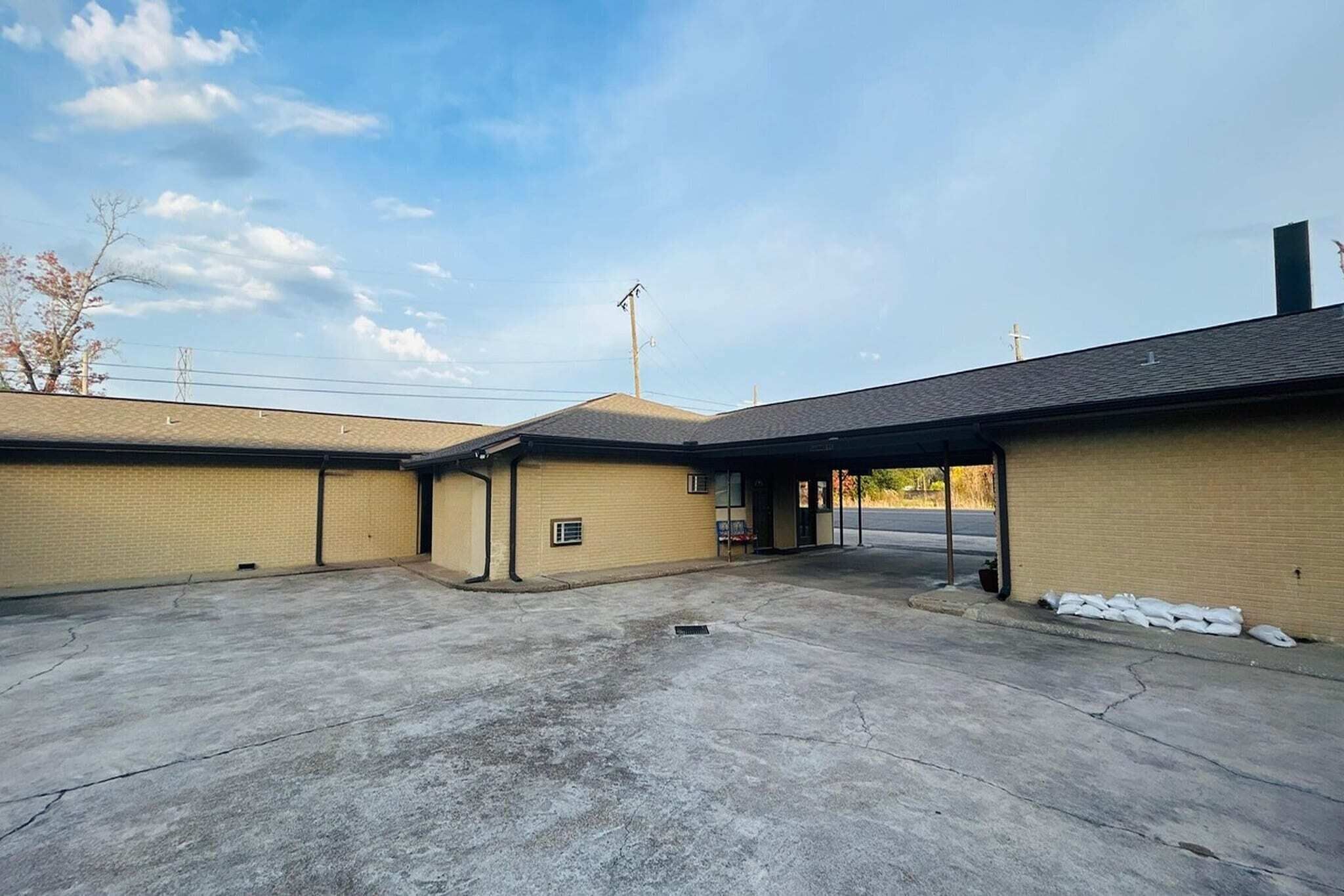 A building with a covered parking area, a brick facade, and a clear sky.