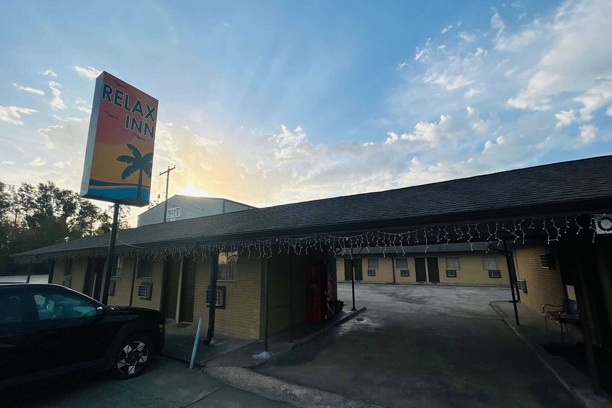 A motel with a sign reading 'Relax Inn,' a covered parking area, and a building with a flat roof.
