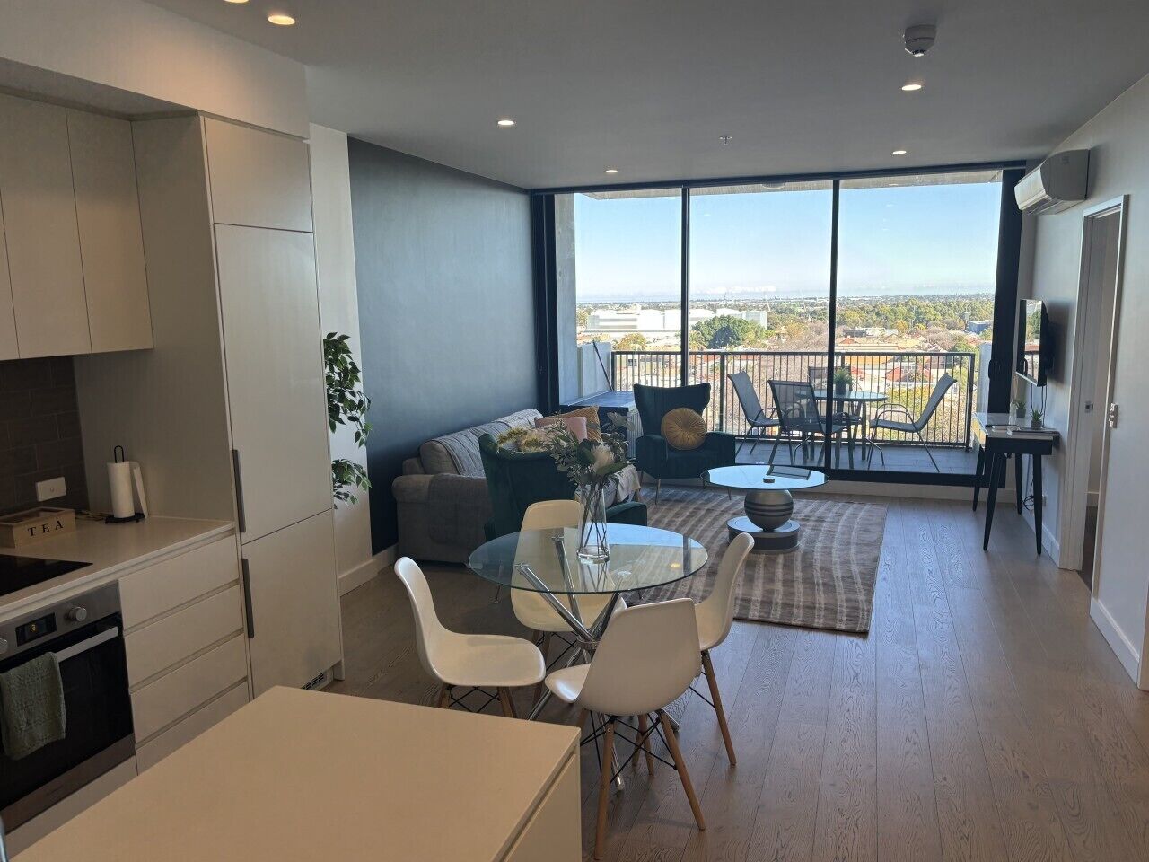 A modern kitchen with a dining area, large windows, and a view of the city.