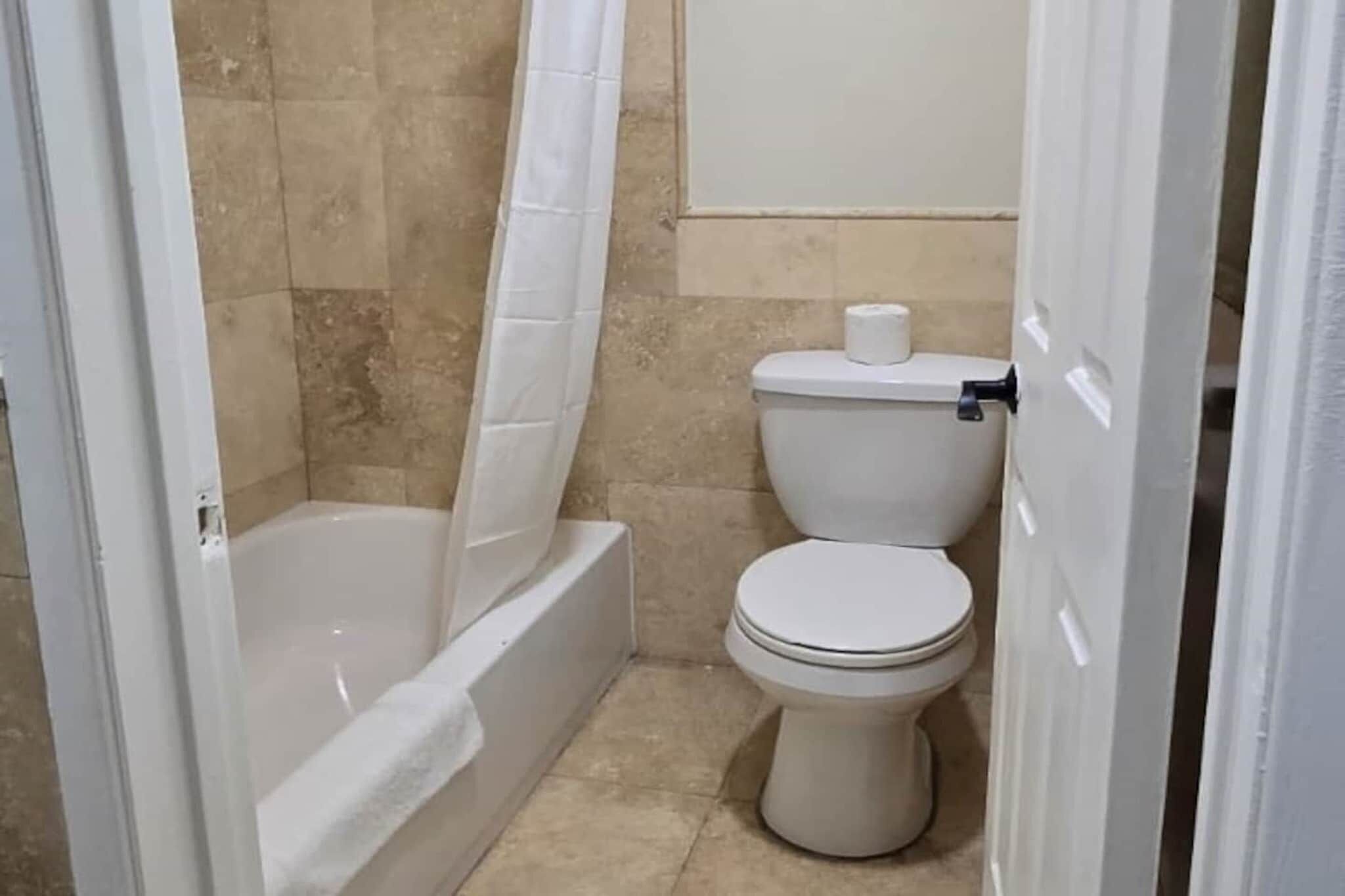 Un bagno con una vasca, un water e una tenda da doccia.