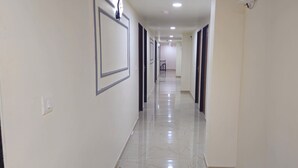 A hallway with white walls, framed pictures, and a tiled floor.