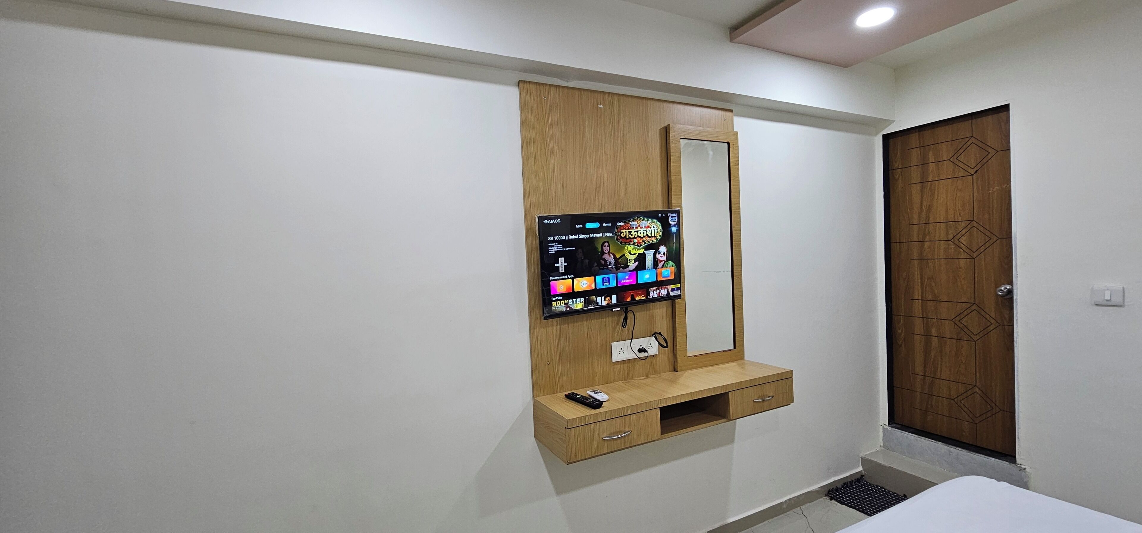 Quarto com guarda-roupa de madeira, televisão montada e mesa de cabeceira.