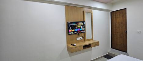 Quarto com guarda-roupa de madeira, televisão montada e mesa de cabeceira.