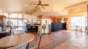 A spacious indoor area with a reception desk, seating arrangements, and a ceiling fan.