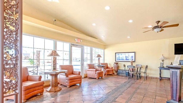 A lobby with seating, a ceiling fan, and a television.