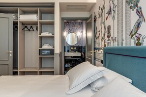 Habitación de hotel con cama, armario, espejo y un detalle decorativo en la pared.