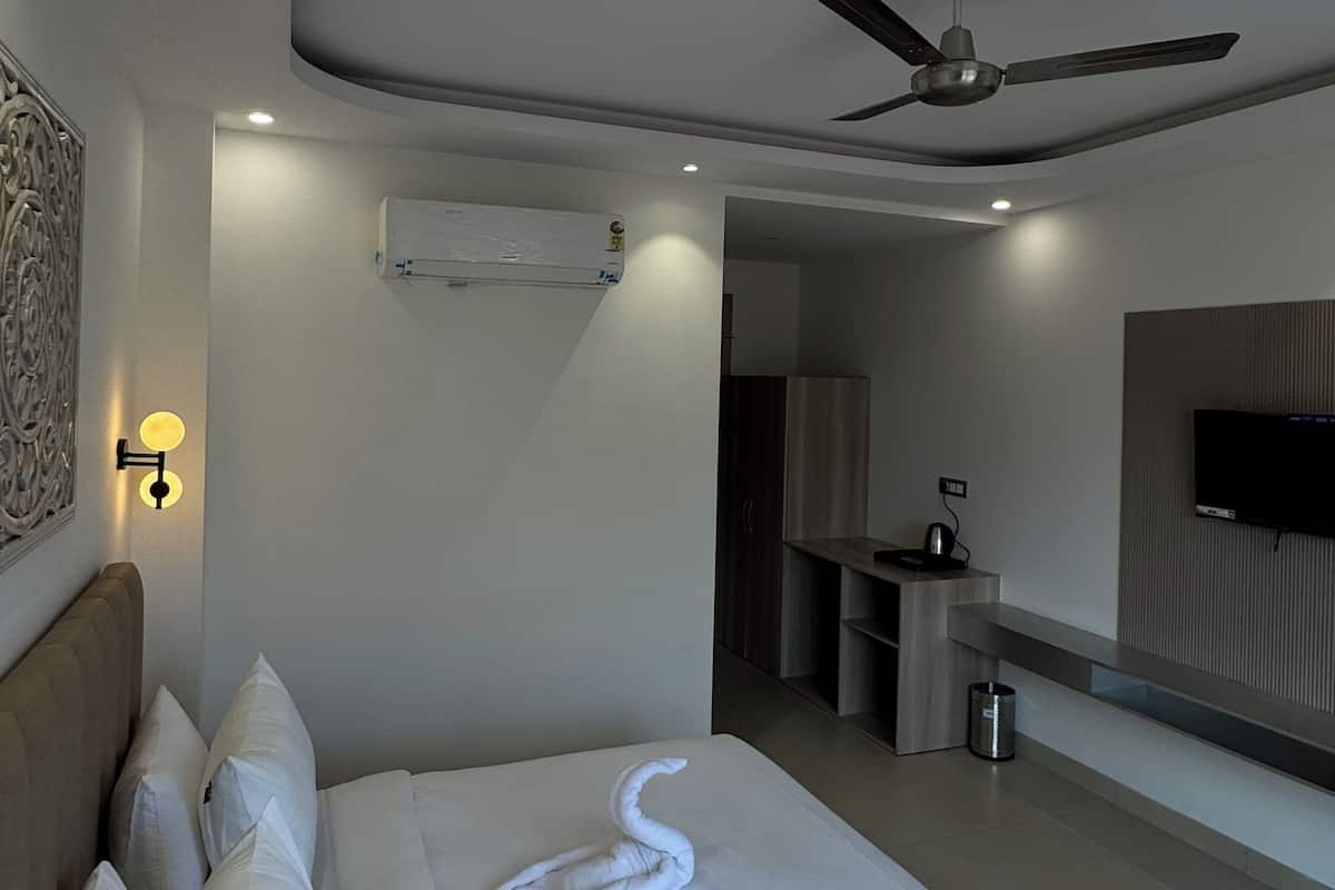Una camera d'hotel moderna con un letto grande, un ventilatore a soffitto, una TV a schermo piatto e un angolo cottura.