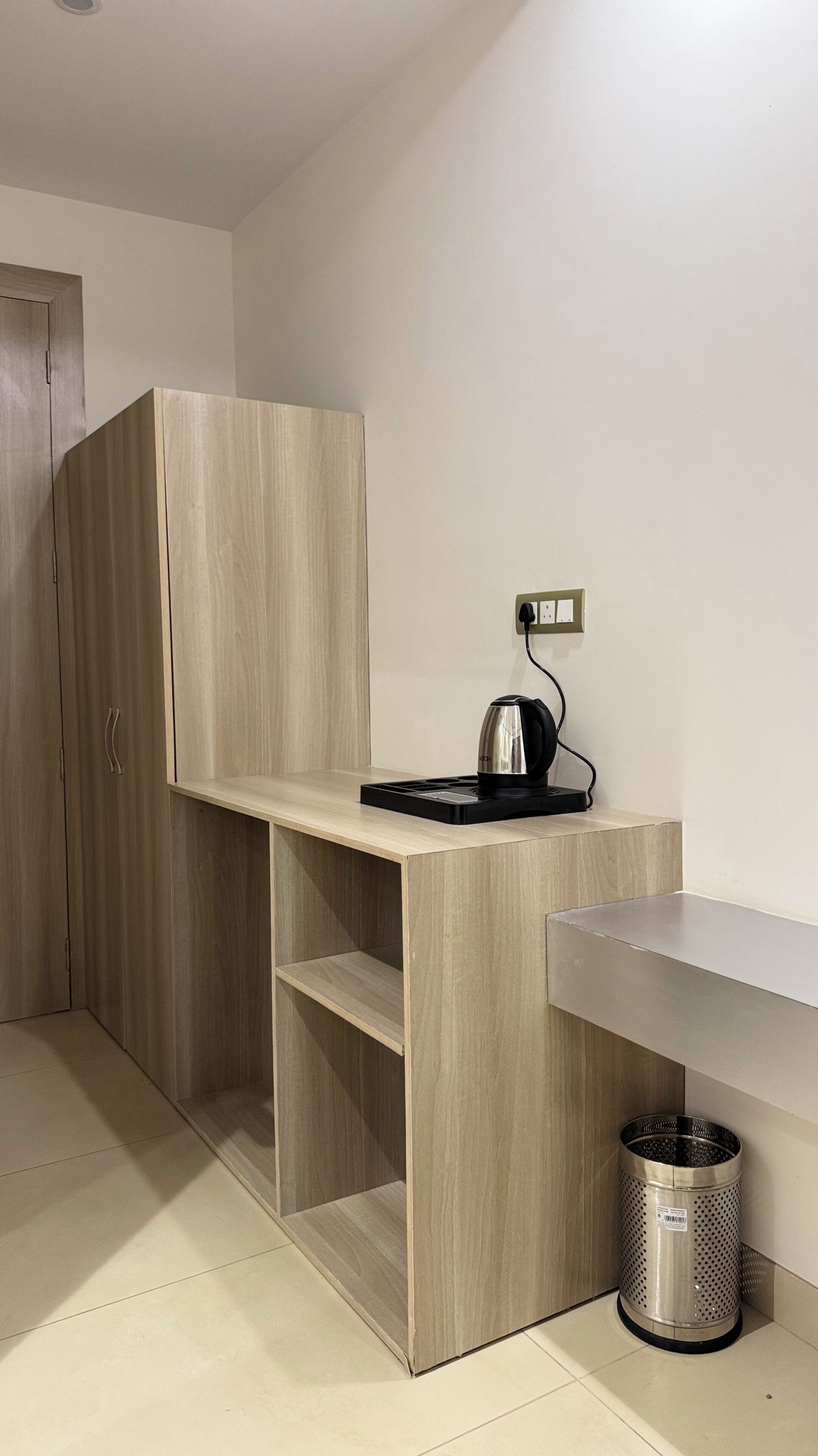 Une petite cuisine moderne équipée d’une cuisinière intégrée, d’une bouilloire et d’une poubelle.