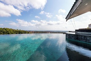 A clear infinity pool with a view of a distant town and mountains. - Villa Ocean's Height By Fays Hospitality (Bali)