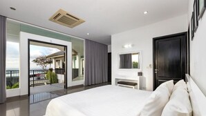 A modern bedroom with a large bed, a TV, and a balcony with a view. - Villa Ocean's Height By Fays Hospitality (Bali)