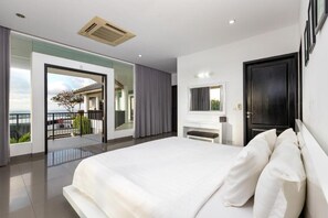 A modern bedroom with a large bed, a TV, and a balcony with a view. - Villa Ocean's Height By Fays Hospitality (Bali)
