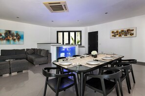 A modern dining area with a long table set for six, surrounded by black chairs. - Villa Ocean's Height By Fays Hospitality (Bali)