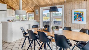 Une cuisine moderne avec un plafond en bois, un coin repas avec des chaises noires et une grande fenêtre.