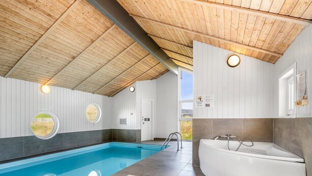 Un espace piscine intérieur moderne, avec une vue dégagée sur le ciel, un jacuzzi et un plafond en bois.