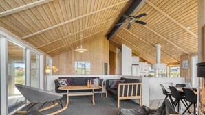 Un intérieur moderne avec un plafond en bois, un canapé, une table à manger et des fauteuils en forme de poire.