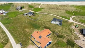 Vue aérienne d’une propriété côtière comprenant plusieurs maisons, une plage de sable et une vue dégagée sur l’océan.