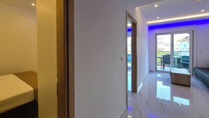 A modern hotel room with a bed, a wooden bench, and a balcony with a view. - 15 - Alexandros Apartments by SDR (Paralia)