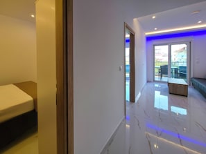 Ein modernes Hotelzimmer mit Bett, einer Holzbank und einem Balkon mit Blick.