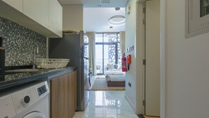 A modern kitchen with a washing machine, a sink, and a window with curtains. - Bloomfields Studio - The Gate Masdar (Abu Dhabi)