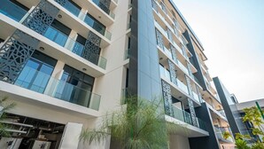 A multi-story building with balconies, large windows, and a modern architectural design. - Bloomfields Studio - The Gate Masdar (Abu Dhabi)