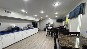 A kitchen with white cabinets, a blue countertop, a marble dining table, and a microwave.