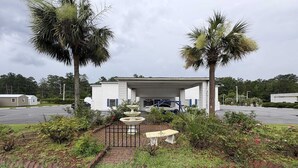 A building with a covered entrance, a fountain, and palm trees.