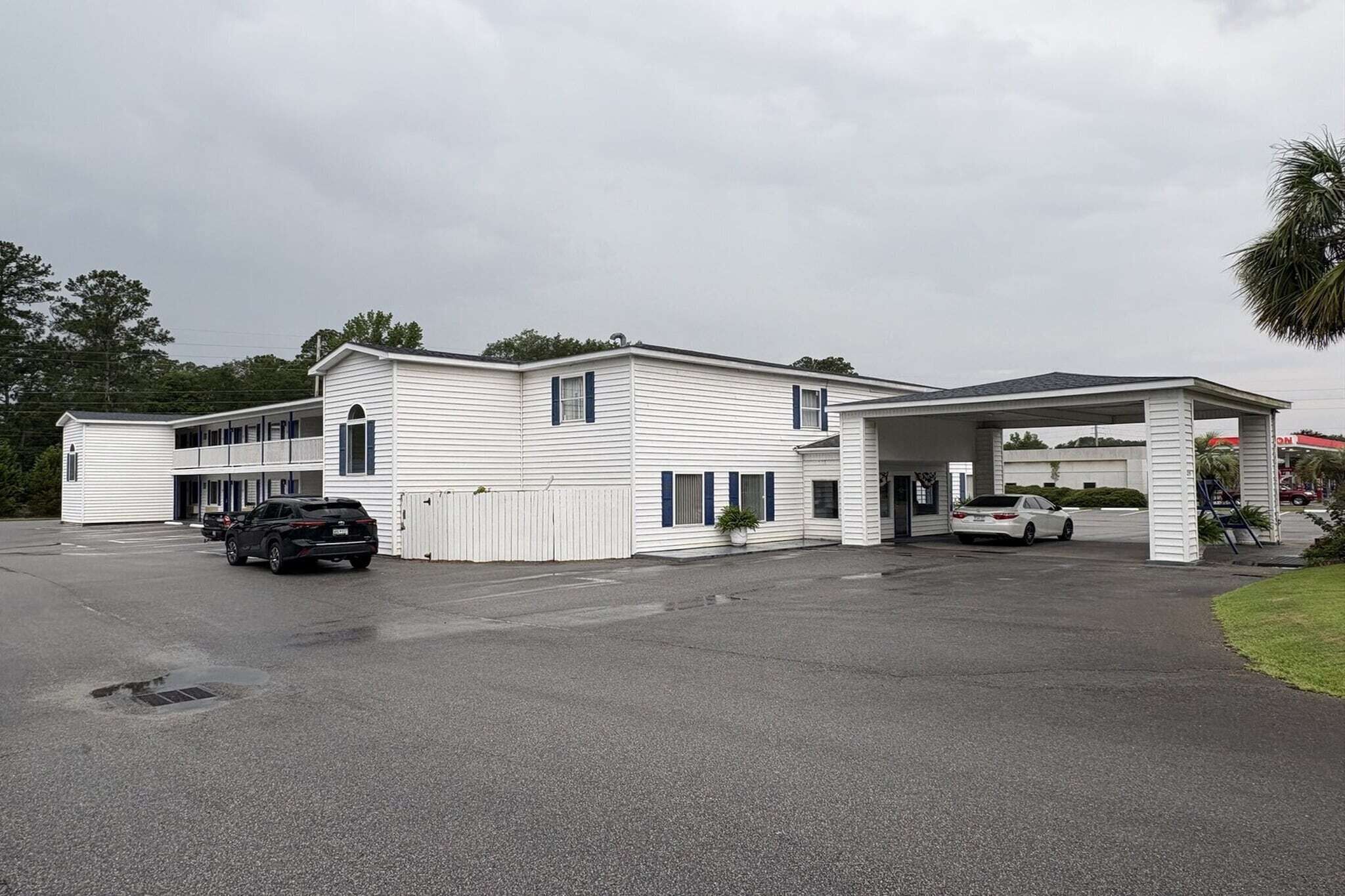 A two-story building with a covered parking area and a gas station attached.