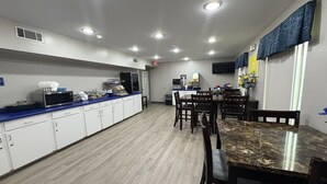 A kitchen with white cabinets, a blue countertop, a marble dining table, and a microwave.