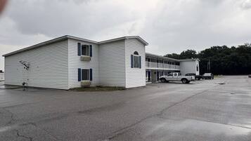 A two-story building with a flat roof, a garage, and a covered parking area.