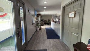 A hotel hallway with a reception desk, a 'Employees Only' sign, a blue mat, and a potted plant.