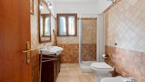A bathroom with a shower, toilet, sink, and a mirror.