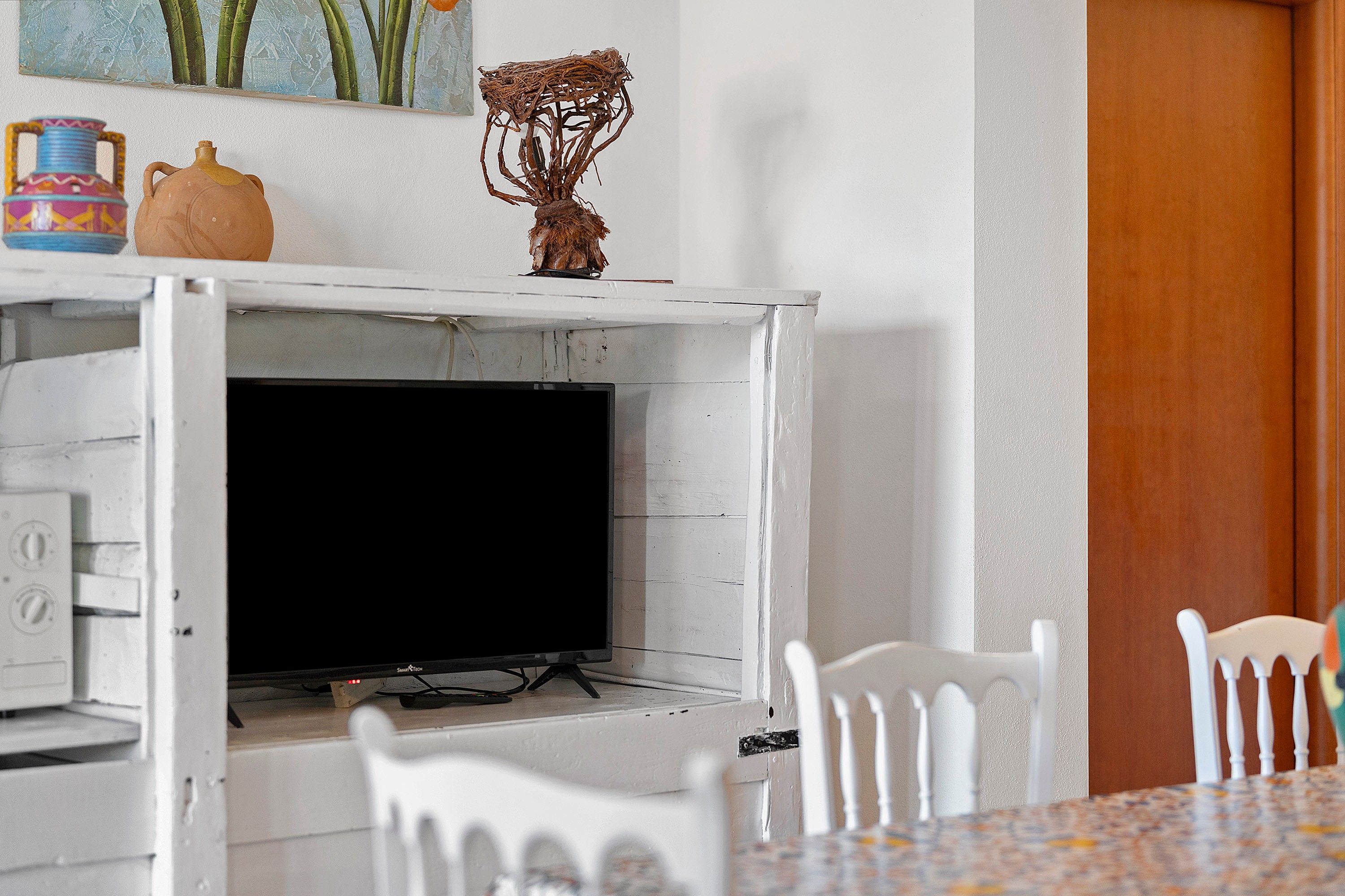 Una habitación con chimenea de ladrillo blanco, televisor y muebles blancos.