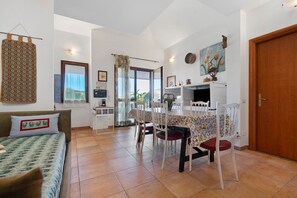 Una habitació acollidora amb llit, taula de menjador, cadires, zona de cuina i una porta.