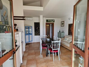 A dining area with a table and chairs, a cabinet, and a sofa. - Apartment 'Masone Verde' with Shared Pool, Wi-Fi and Air Conditioning (Castiadas)