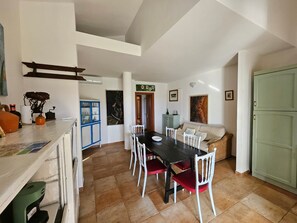 A dining area with a black table, white chairs, a sofa, and a cabinet. - Apartment 'Masone Verde' with Shared Pool, Wi-Fi and Air Conditioning (Castiadas)