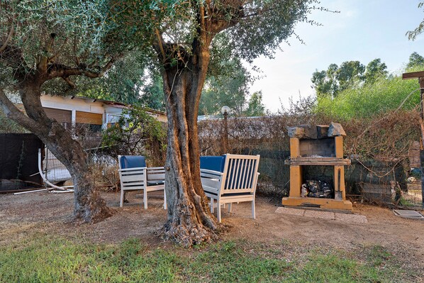 A tree with a bench and a stone structure in a garden setting.
