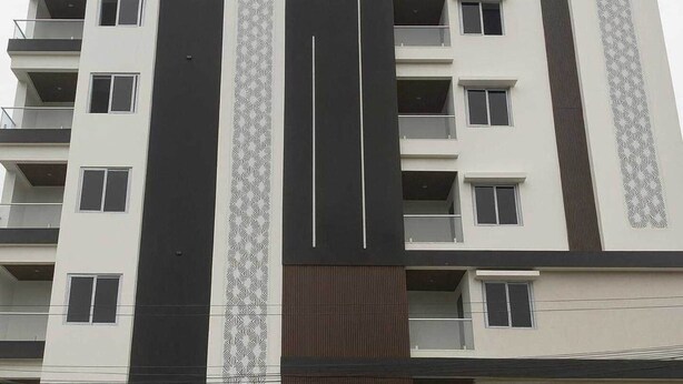 En byggnad med flera våningar, balkonger, ett centralt, vertikalt designelement och en fasad med ett mönster.