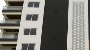 En byggnad med flera våningar, balkonger, stora fönster och ett mönstrat, dekorativt element på fasaden.