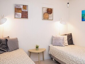 A room with two beds, a small table with a plant, and artwork on the walls. - 4 Star Holiday Home in Hejls (Hejls)