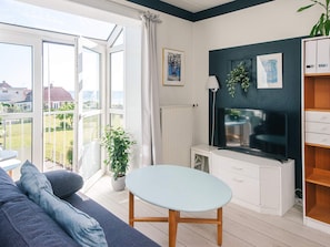 A modern living room with a sofa, a table, a TV, and a view of the outdoors. - 4 Star Holiday Home in Hejls (Hejls)