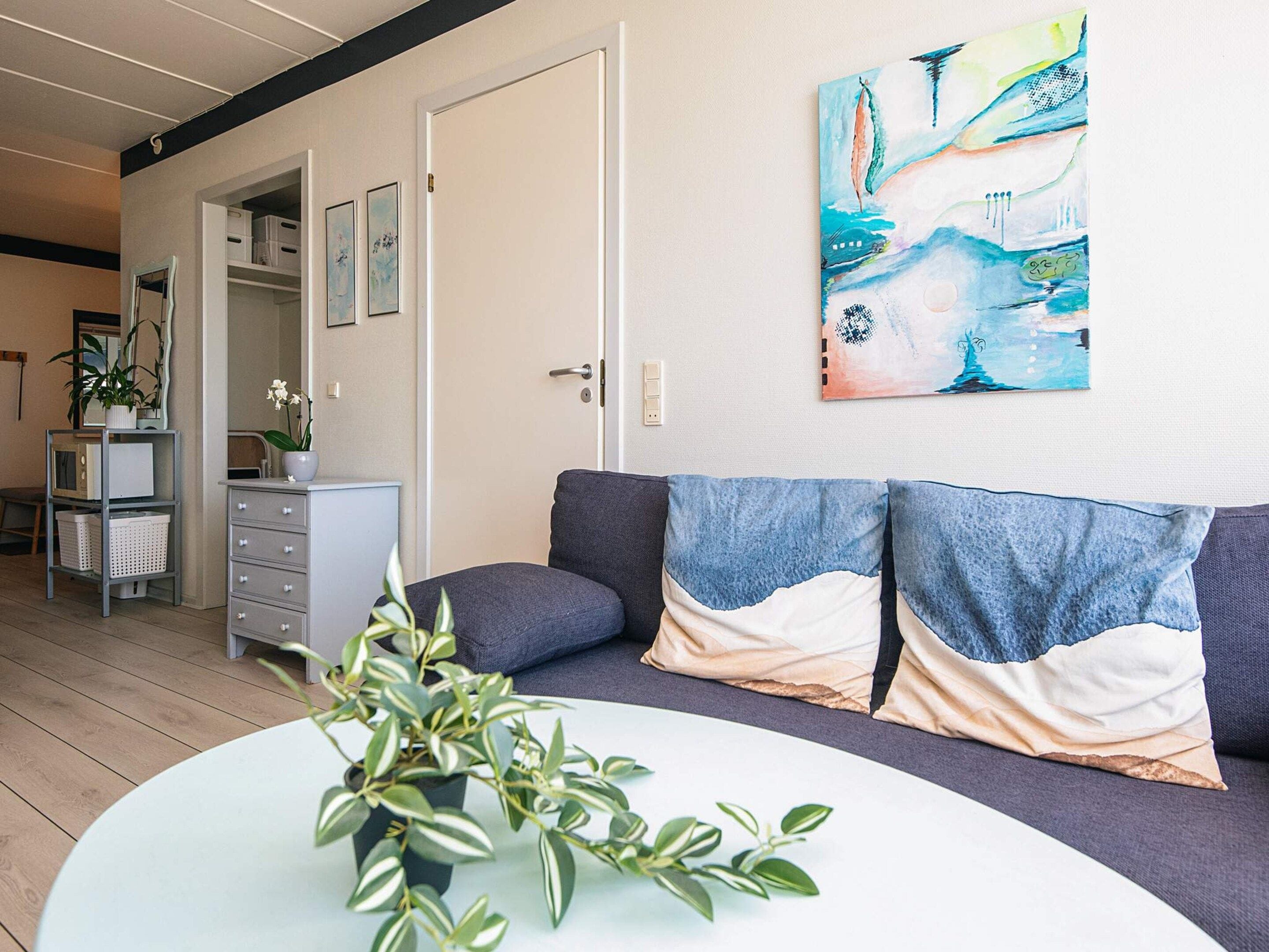 A modern living room with a sofa, a coffee table, and a painting on the wall.
