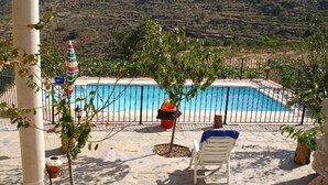 Una piscina con vistas al campo, una silla y plantas en macetas.
