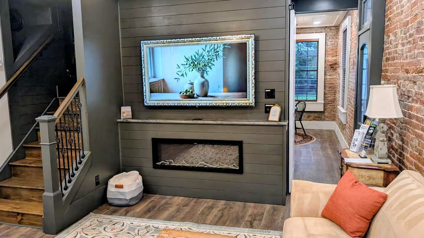 A living room with a fireplace, a television mounted above it, and a staircase leading to another level.